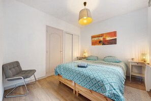 A bedroom with a bed, a chair, a desk, and a painting on the wall. - Charming Apartment in the Heart of the Artists’ District (Camaret-sur-Mer)