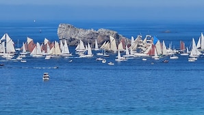 A coastal scene with numerous sailboats anchored near a rocky outcrop. - Comfortable, Cozy Apartment in Camaret (Camaret-sur-Mer)