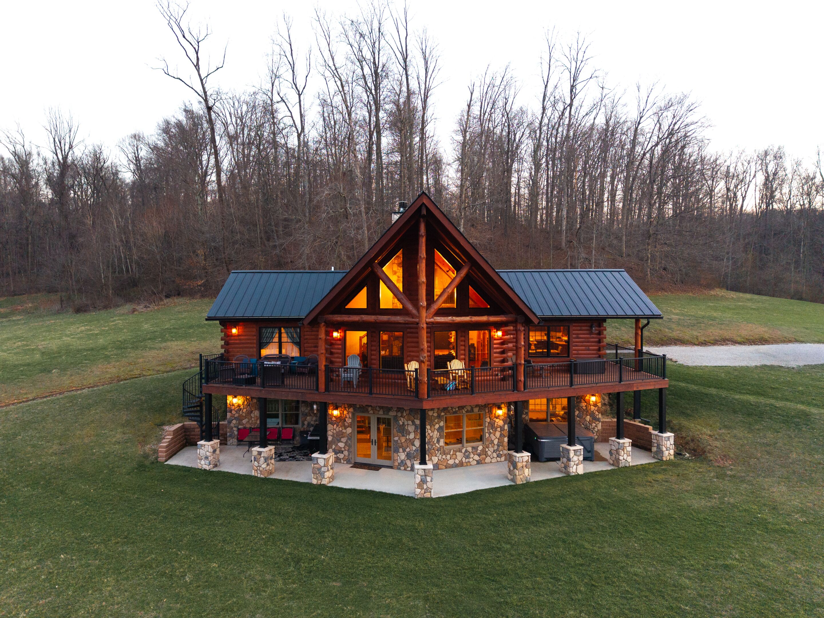 A log cabin with a stone foundation, a balcony, and a porch with outdoor seating.
