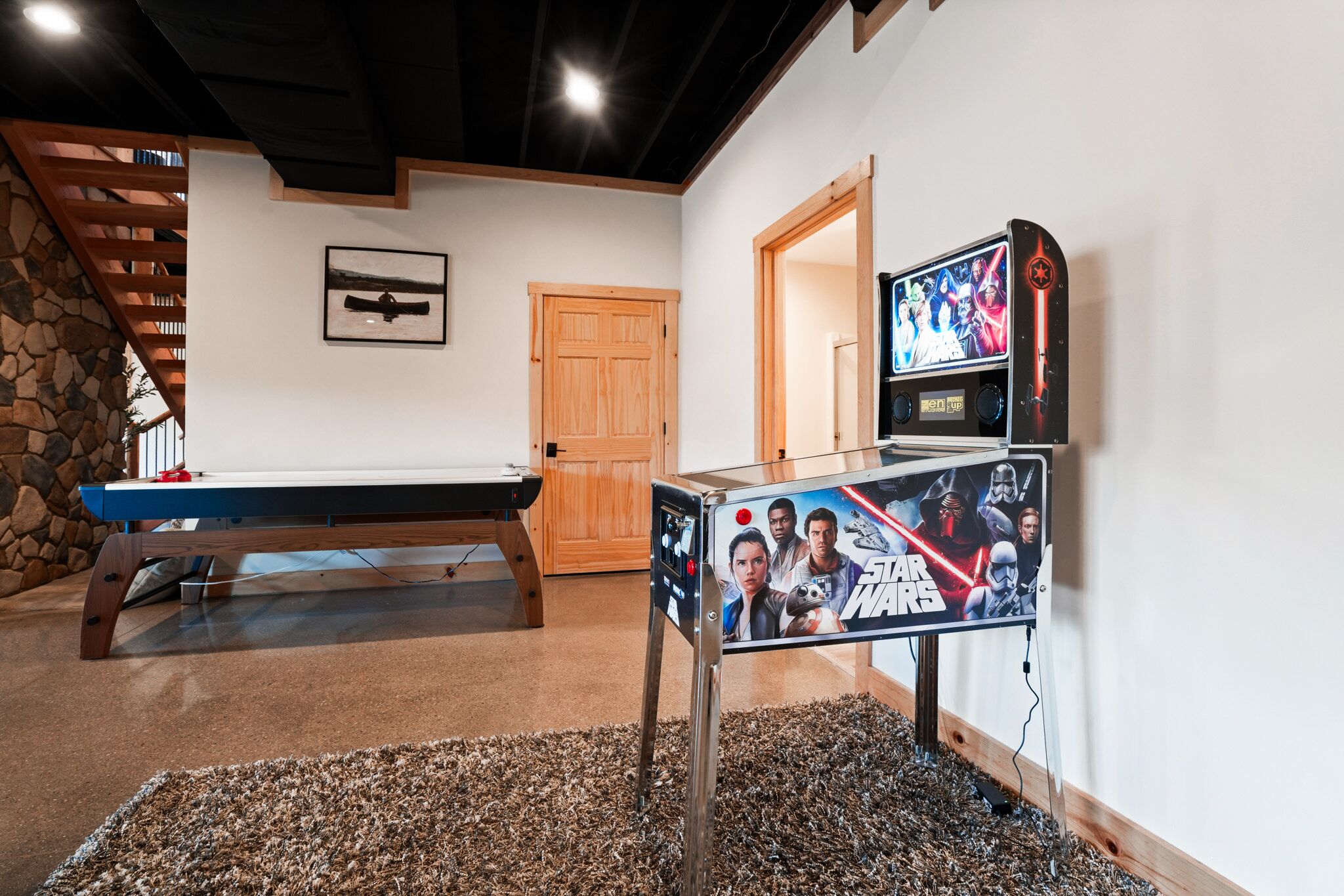 A pool table, a Star Wars poster, a wooden door, and a stone wall.