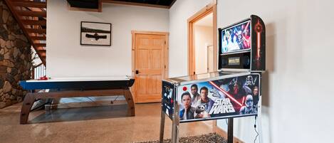 A pool table, a Star Wars poster, a wooden door, and a stone wall.