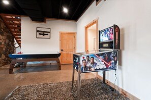 A pool table, a Star Wars poster, a wooden door, and a stone wall.