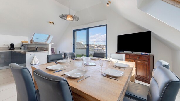 Una cocina moderna con comedor, ventanas amplias y un televisor de pantalla plana.