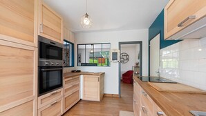 Eine moderne Küche mit Holzausstattung, einem Einbauofen, einer Arbeitsplatte und einer Pendelleuchte.