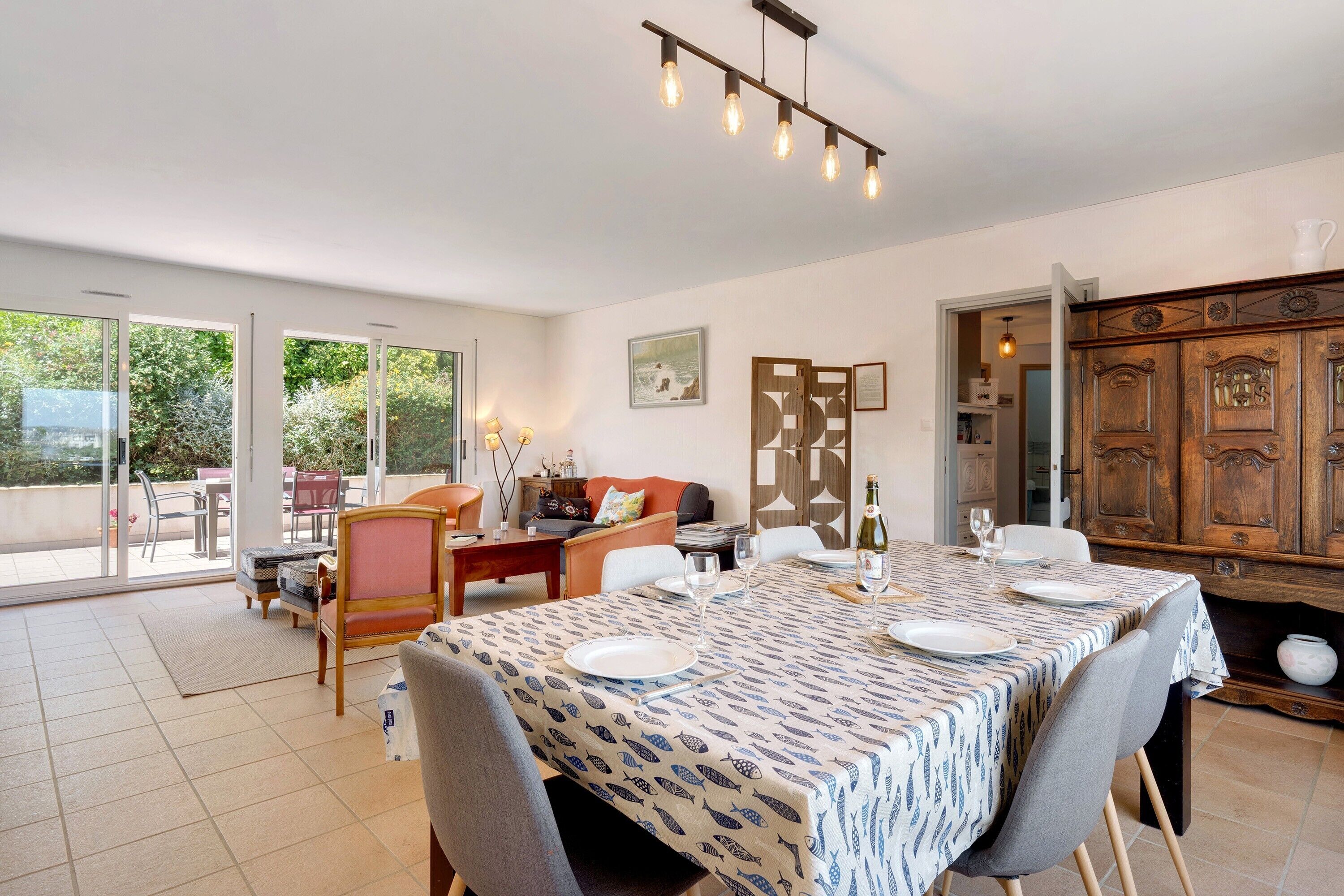 A dining area with a table set for four, a sofa, and a wooden cabinet.