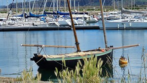Een jachthaven met aan wal liggende boten, kalm water en gazon.