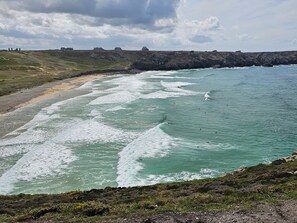 Eine Küstenlandschaft mit Strand, Wellen und felsigen Klippen.