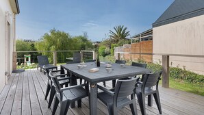 Een terras buiten, met een rechthoekige tafel en stoelen, omringd door een houten terras.