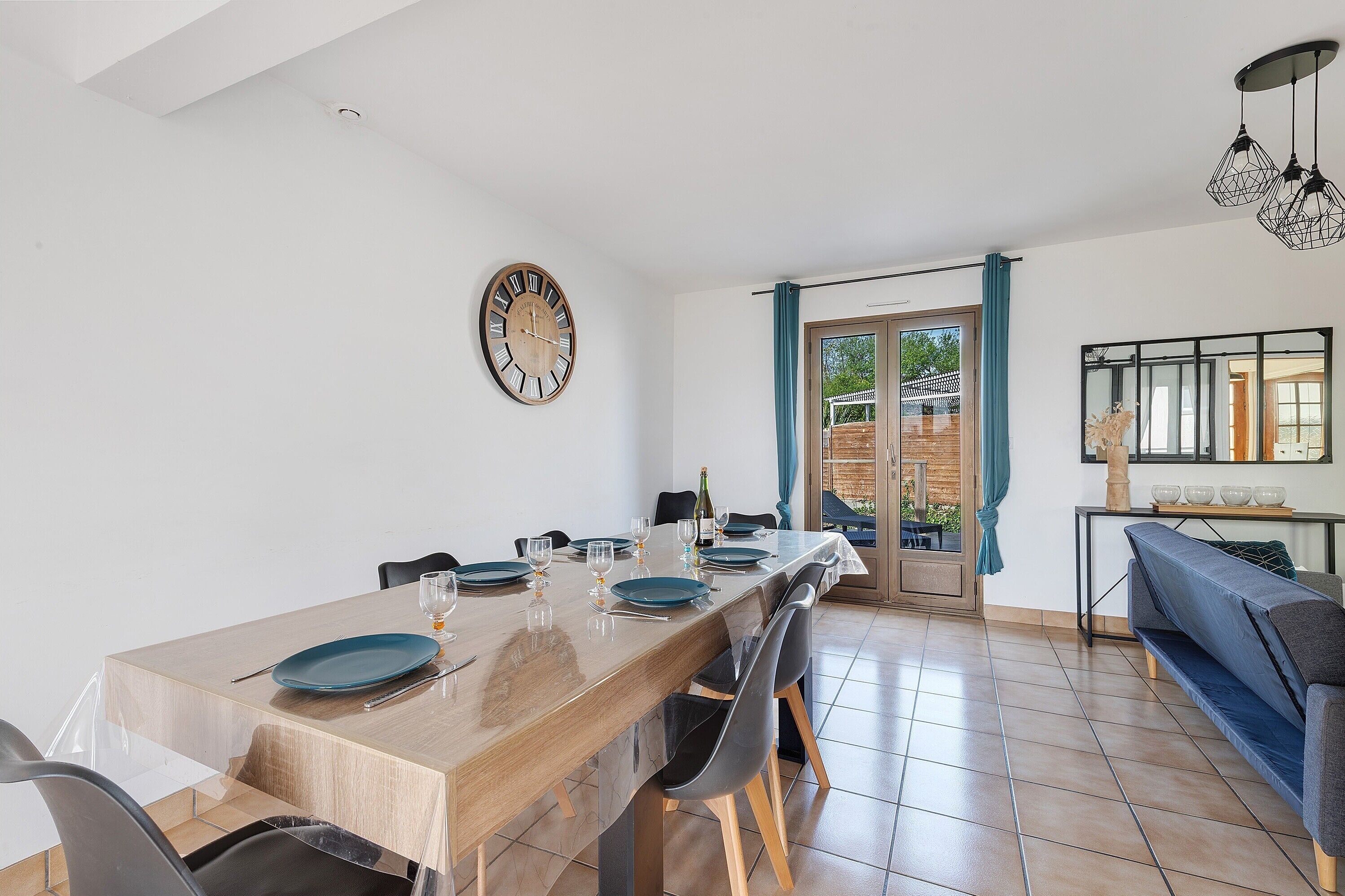 Un comedor con una mesa de madera, sillas y un reloj en la pared.