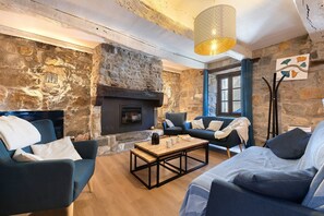 Une pièce chaleureuse avec des murs en pierre, une cheminée, une table basse en bois et des meubles bleus.