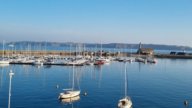 Un port de plaisance où sont amarrés de nombreux bateaux, avec une eau calme et un ciel dégagé.