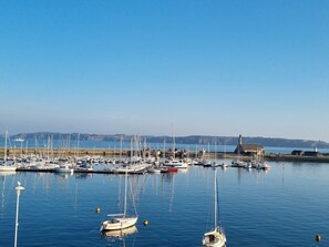 Ein Yachthafen mit mehreren Schiffen, ruhigem Wasser und blauem Himmel.