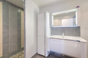 Un baño moderno con ducha, inodoro y lavamanos con espejo.
