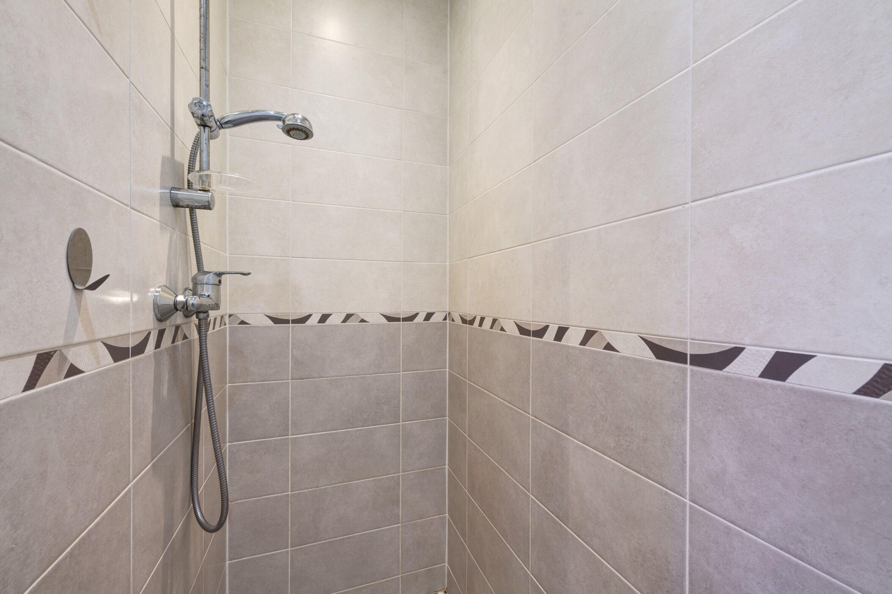 A shower area with tiled walls and a showerhead.