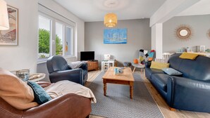 Una sala de estar moderna con sofá, sillón, mesa de centro y televisor.