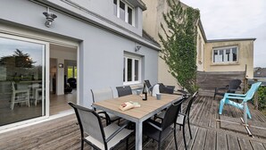 Una terraza de madera con una mesa, sillas, una botella y un menú.