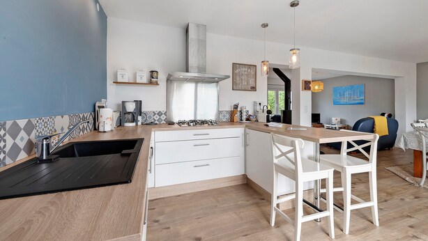 Una cocina moderna con estufa integrada, armarios blancos y encimera de madera.