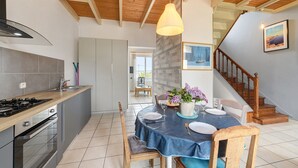 A modern kitchen with a wooden ceiling, a dining area with a table set for two, and a staircase leading to an upper level. - Sea View, Authentic Fisherman's House (Camaret-sur-Mer)