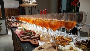 Ett långt bord med flera glas fyllda med en bärnstensfärgad vätska, olika sorters mat och en träbricka.