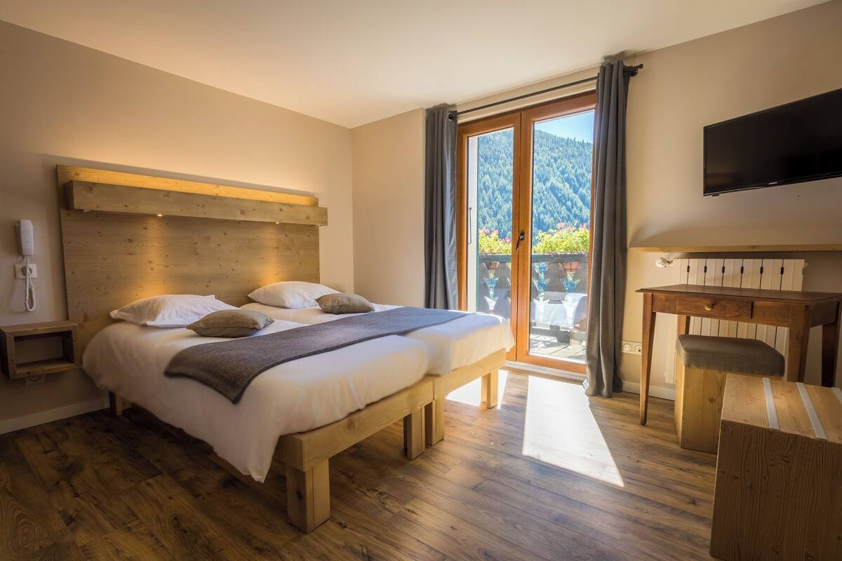 A bedroom with a wooden bed, a desk, and a TV.