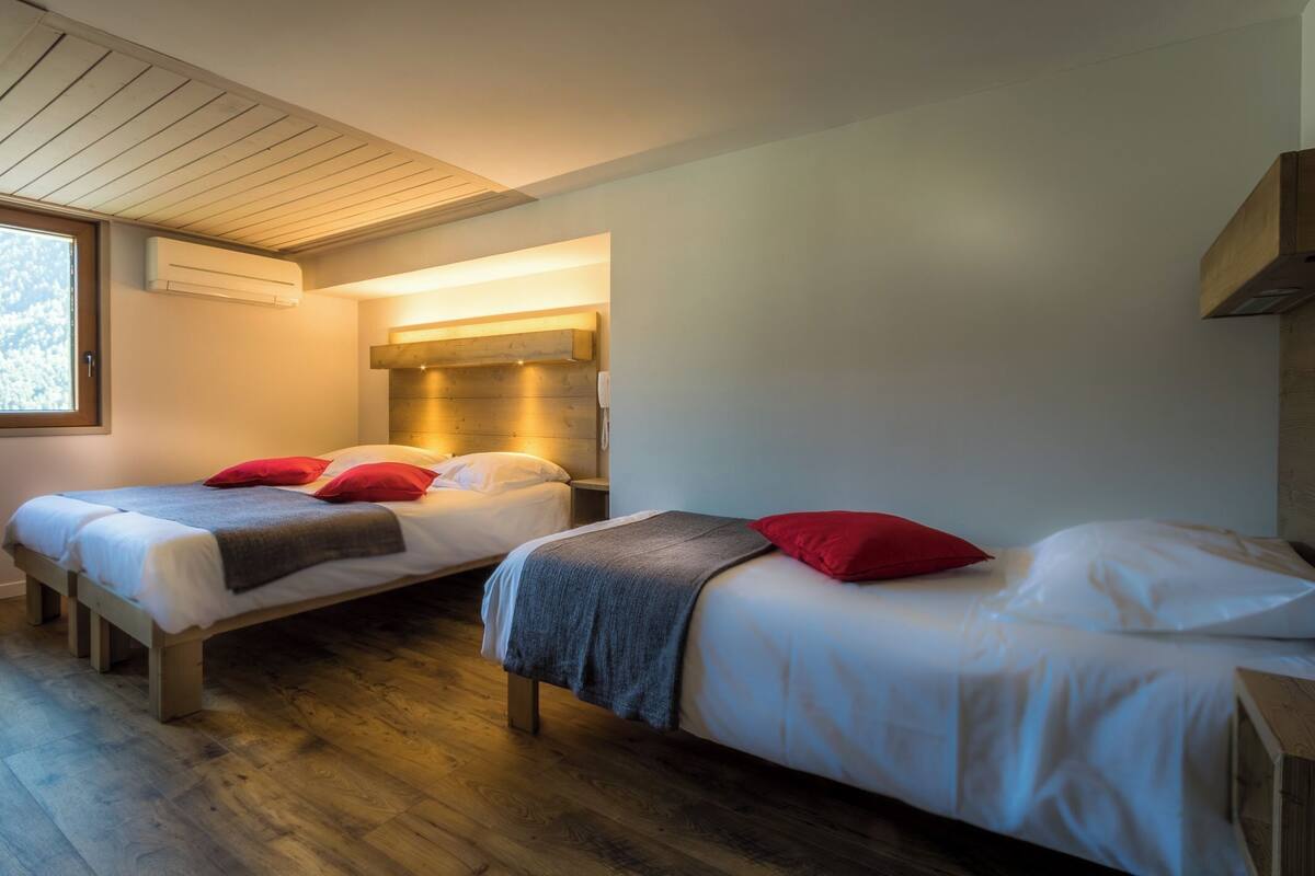 A modern bedroom with two beds, wooden flooring, and a built-in heater.
