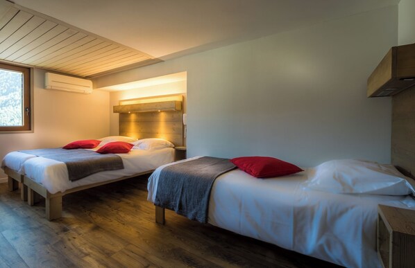 A modern bedroom with two beds, wooden flooring, and a built-in heater. - hotel le Malgovert (Séez)