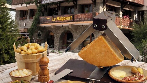 En byggnad av trä med en skylt där det står ”Hotel Malcovert” och ”Restaurang Le Malcovert”.