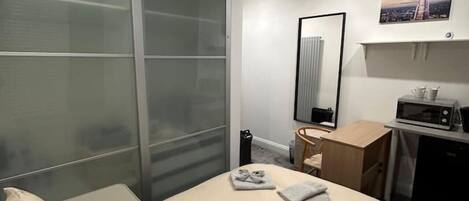 A modern hotel room with a large bed, a desk, a mirror, and a microwave.