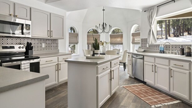 A modern kitchen with white cabinetry, a central island, and a large window.