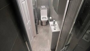 A narrow, modern bathroom with a toilet, sink, and shower. - Central London 5 min to metro (Greater London)