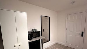 A bedroom with a wardrobe, a small desk with a mirror, and a door. - Central London 5 min to metro (Greater London)