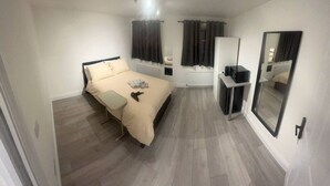 A bedroom with a bed, bedside table, and a mirror. - Central London 5 min to metro (Greater London)