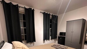 Un dormitorio con una cama grande, un armario, un radiador y un escritorio con una silla.