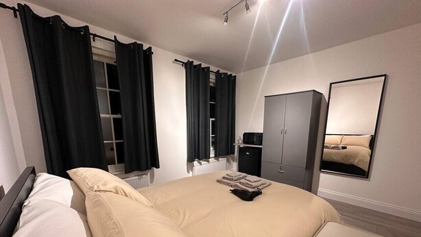 Un dormitorio moderno con una cama grande, una mesita de noche, un armario y un espejo.