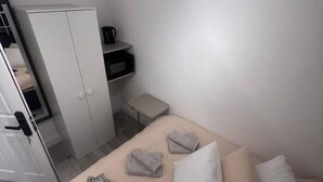 Et hotelværelse med seng, garderobeskab, lille bord og stol.