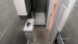 Ein modernes Badezimmer mit einer Glaskabine zur Dusche, einem weißen Waschbecken und einem Handtuchhalter.