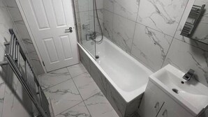 Une salle de bain moderne avec une douche à parois de verre, une baignoire sur pieds, des toilettes et un lavabo.