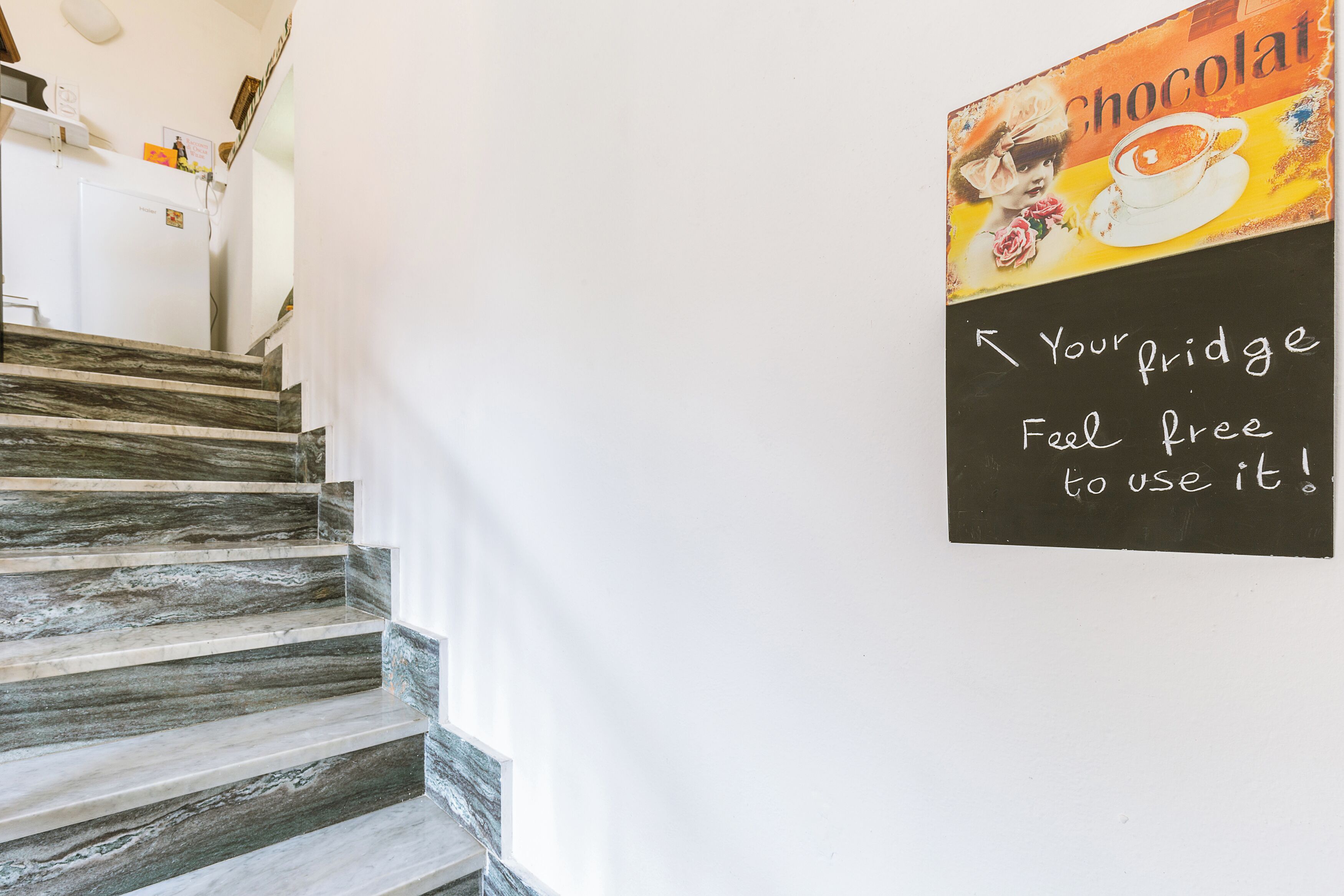 Una escalera con detalles de mármol y un cartel en la pared que dice 'Your fridge feel free to use it!'