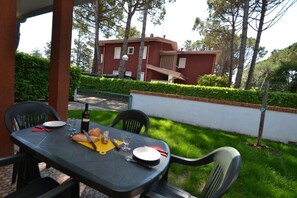 An outdoor dining table with chairs, a bottle, and a plate of food. - Cozy Villa With Garden (San Michele al Tagliamento)