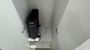 A white electrical panel with a black device, a cable, and a label. - Flat with Bathroom and Kitchen (Greater London)
