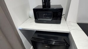 A compact kitchenette with a microwave, coffee maker, and a small refrigerator. - Flat with Bathroom and Kitchen (Greater London)