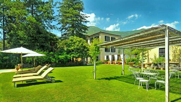 Ein gepflegter Rasen, ein Sitzbereich im Freien und ein Gebäude mit einer Pergola.
