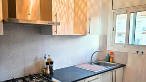 Een moderne keuken met een gasfornuis, een roestvrijstalen spoelbak en houten kastjes.