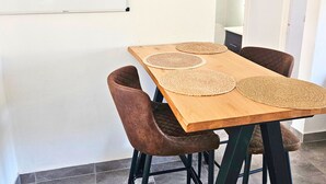 Een eethoek met een houten tafel, vier bruine stoelen en twee geweven placemats.