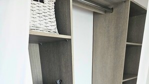 Een inloopkast met houten planken, een kledingroede en een deur.