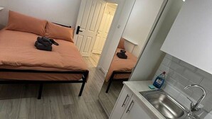 A compact room with a bed, a small kitchenette, and a door leading to another room. - Room 5 minute Walk to Waterloo (Greater London)