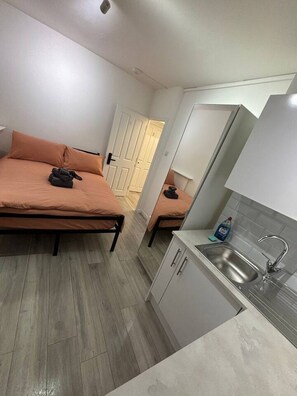 A compact room with a bed, a small kitchenette, and a door leading to another room. - Room 5 minute Walk to Waterloo (Greater London)