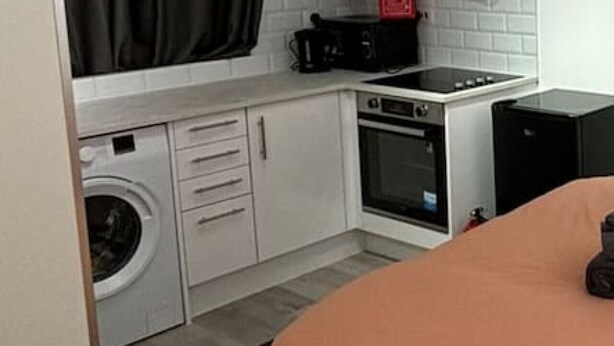 A compact kitchen with a washing machine, a microwave, and a stove. - Room 5 minute Walk to Waterloo (Greater London)