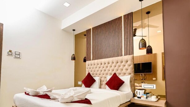 Una habitación de hotel moderna con una cama grande, un televisor de pantalla plana y una mesita de noche de madera.