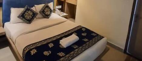 Une chambre d’hôtel équipée d’un lit, d’un ventilateur de plafond, d’un climatiseur et d’une table de chevet avec une lampe.